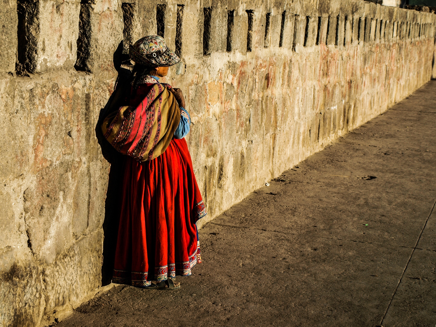 Traditional dress worn by a child on a wall, Ecuador