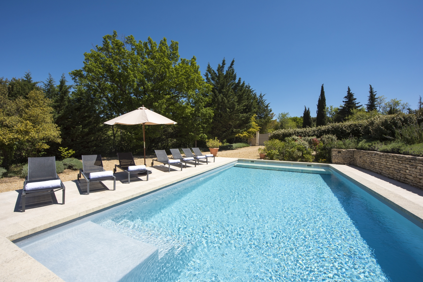Pool and pool area with sun loungers, towels and umbrellas at Mas du Buis in Provence, France