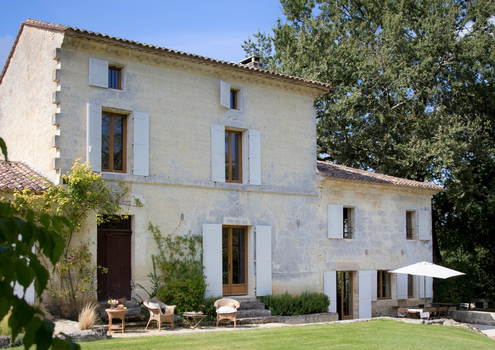 Façade and front garden with plants, coffee tables and comfy chairs at La Colline Bleue in South West France