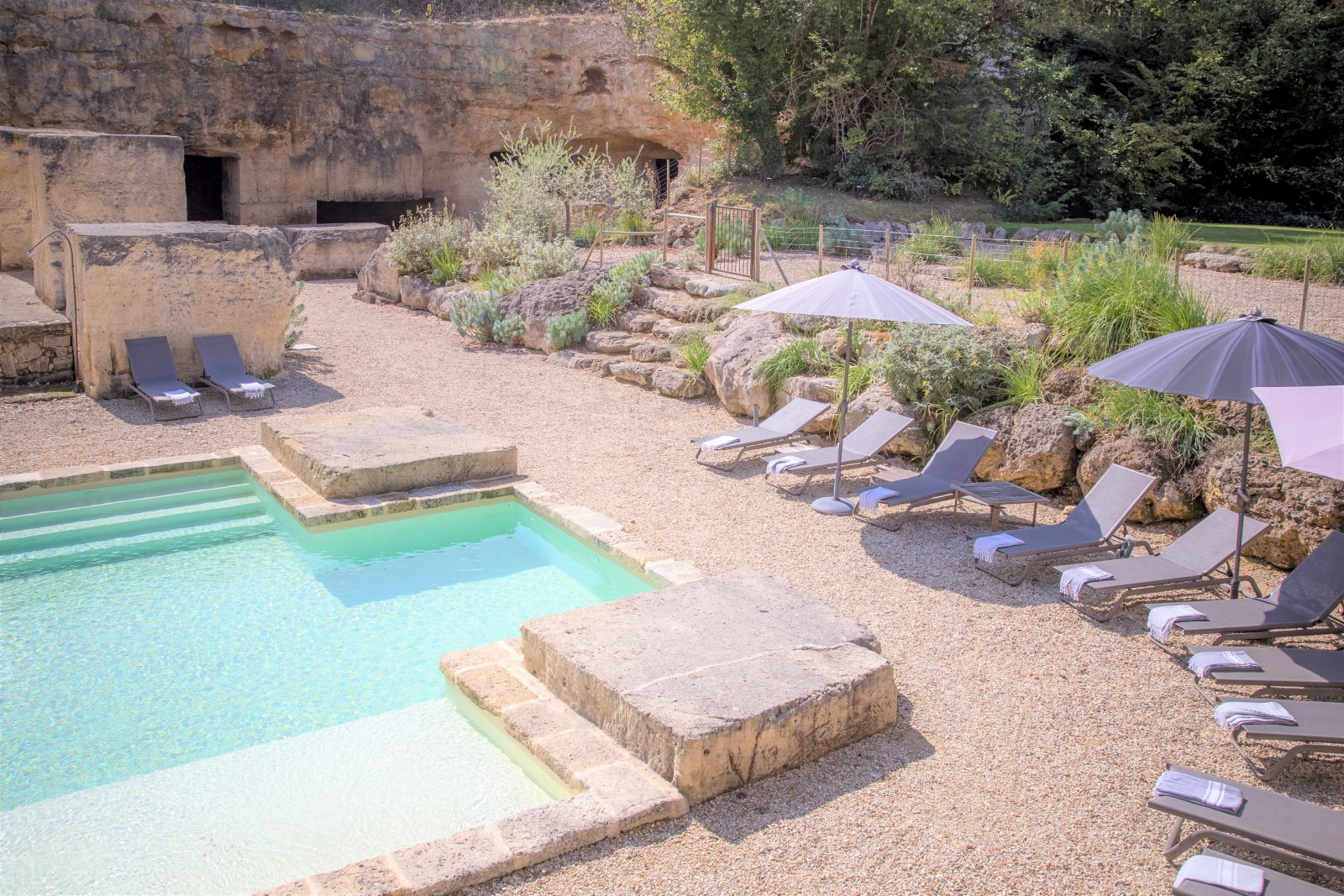 Pool and gated pool area with sun loungers, umbrellas and plants at La Colline Bleue in South West France