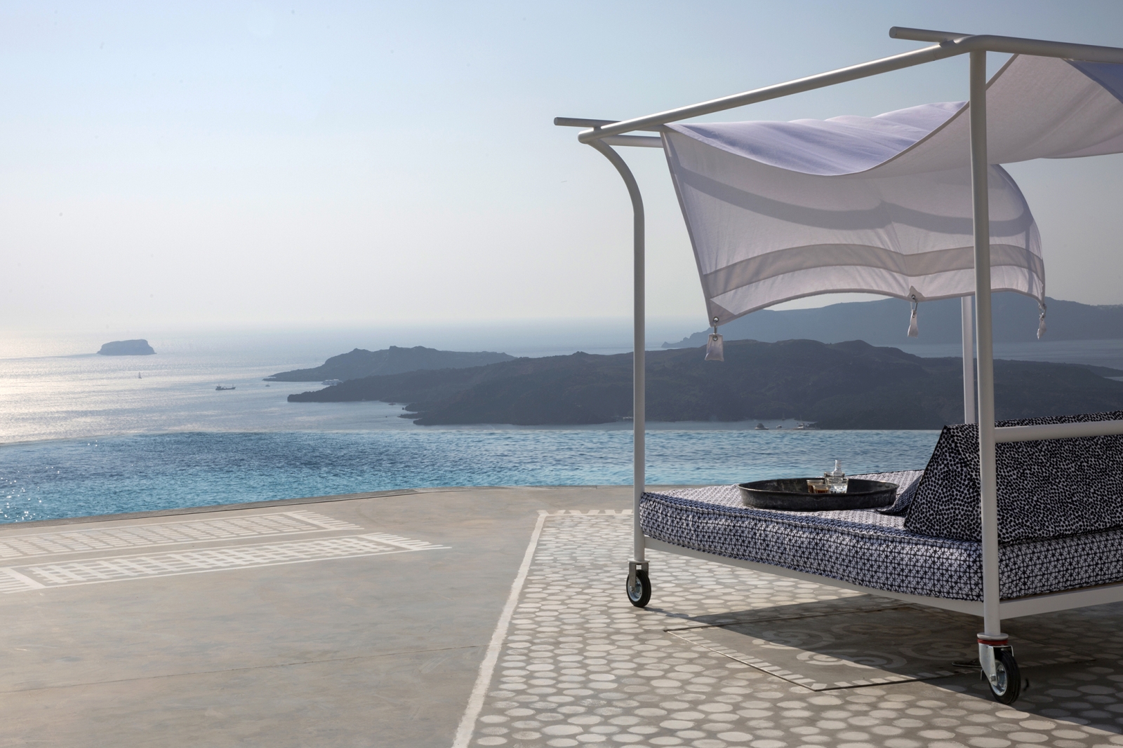 Day bed with sea view on terrace by infinity pool at Erosantorini on Santorini, Greece