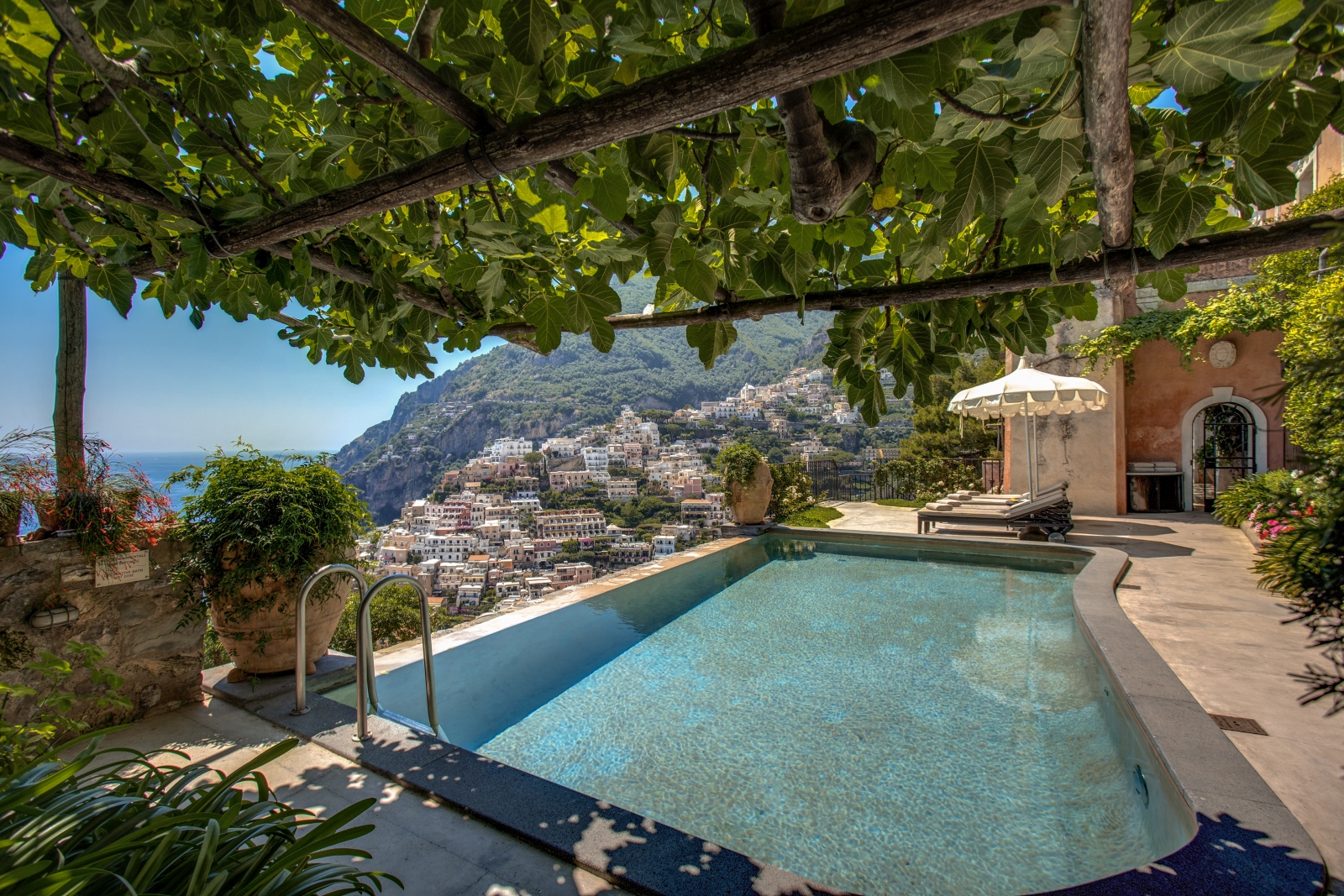 Pool with shaded seating and view towards Amalfi