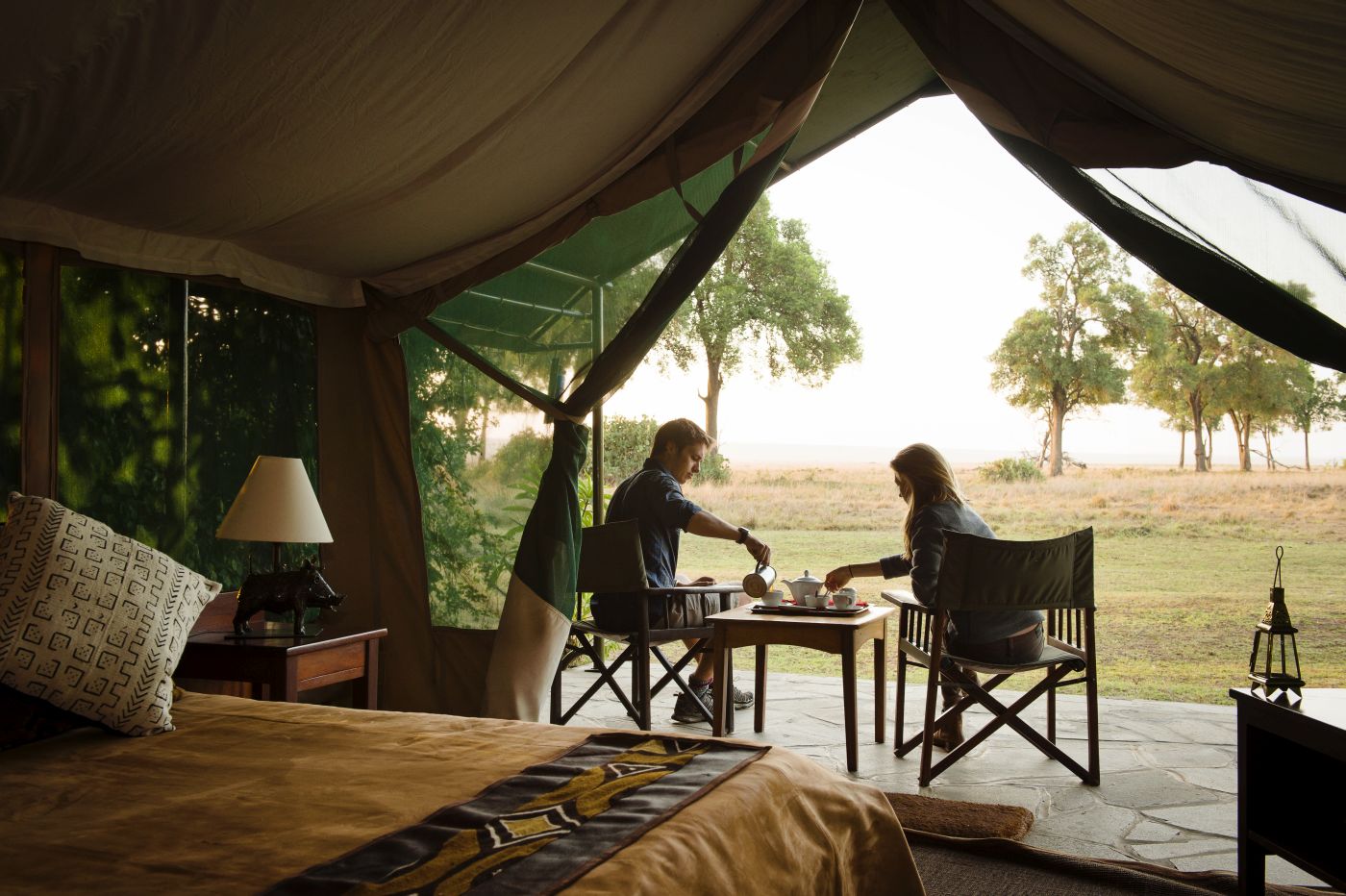A couple sitting having tea at the front of their luxury tent at Governors Camp in Kenya