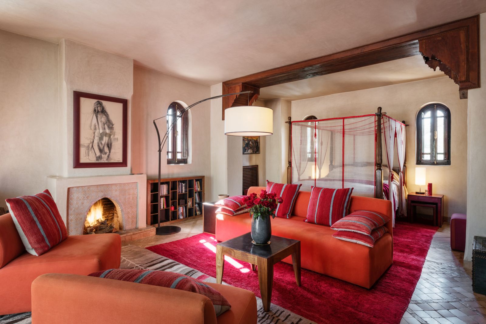 The Perla Suite with four poster bed, sofa, chairs and an open fire at Dar Zemora in Morocco