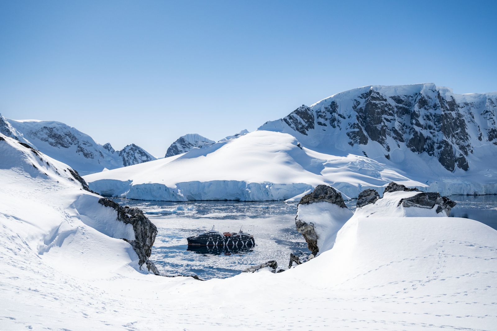 Distant view of the Magellan Explorer in Antarctica surrounded by snowy landscapes
