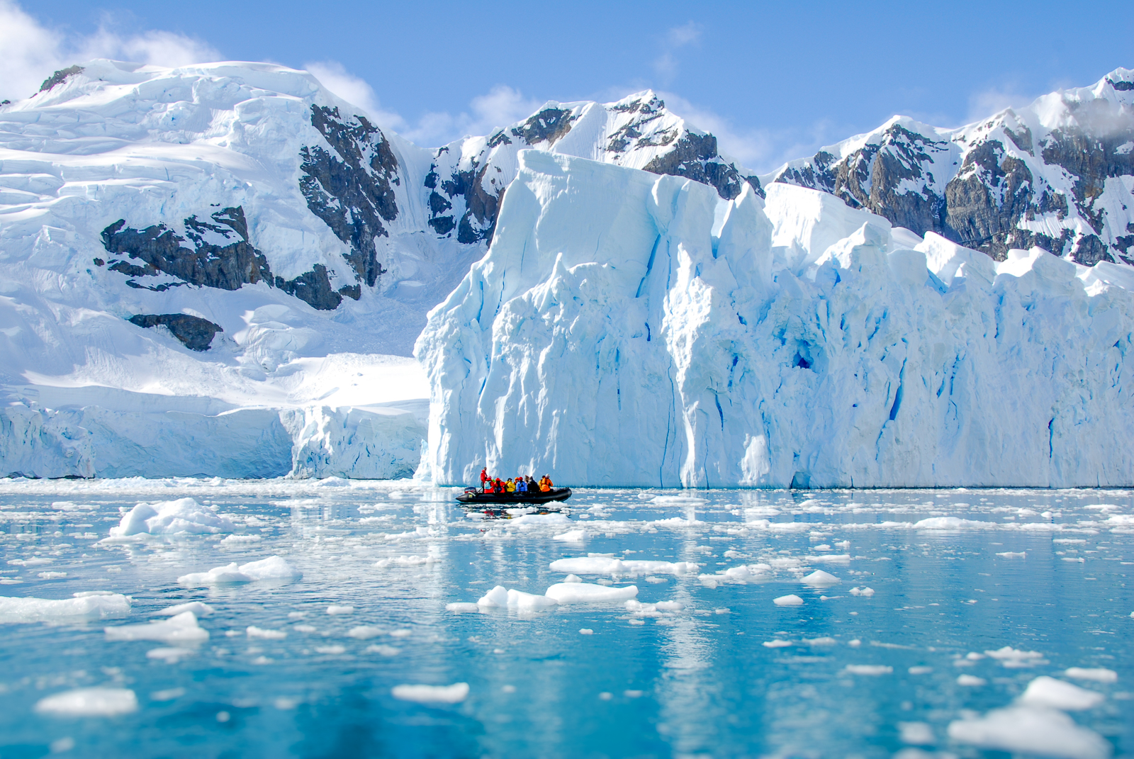 A zodiac cruising past icy cliffs in Antarctica