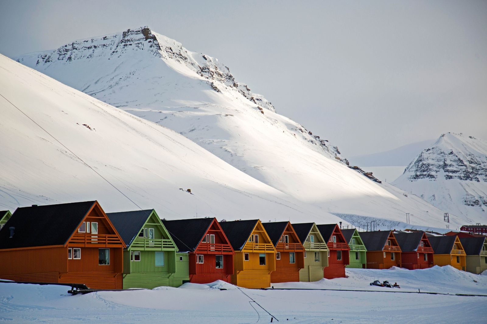 Colourful painted huts in front of snow covered mountains in Longyearbyen Norway