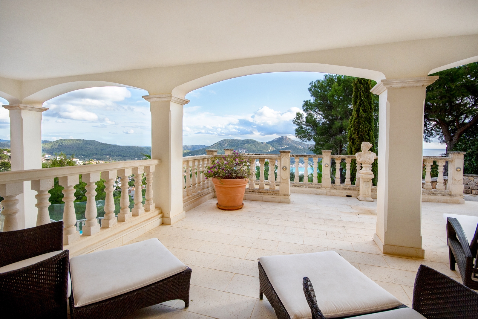 Balcony with sun loungers, stone archways, statue, flowers & harbour & mountain view at Casa Verano in Mallorca, Spain