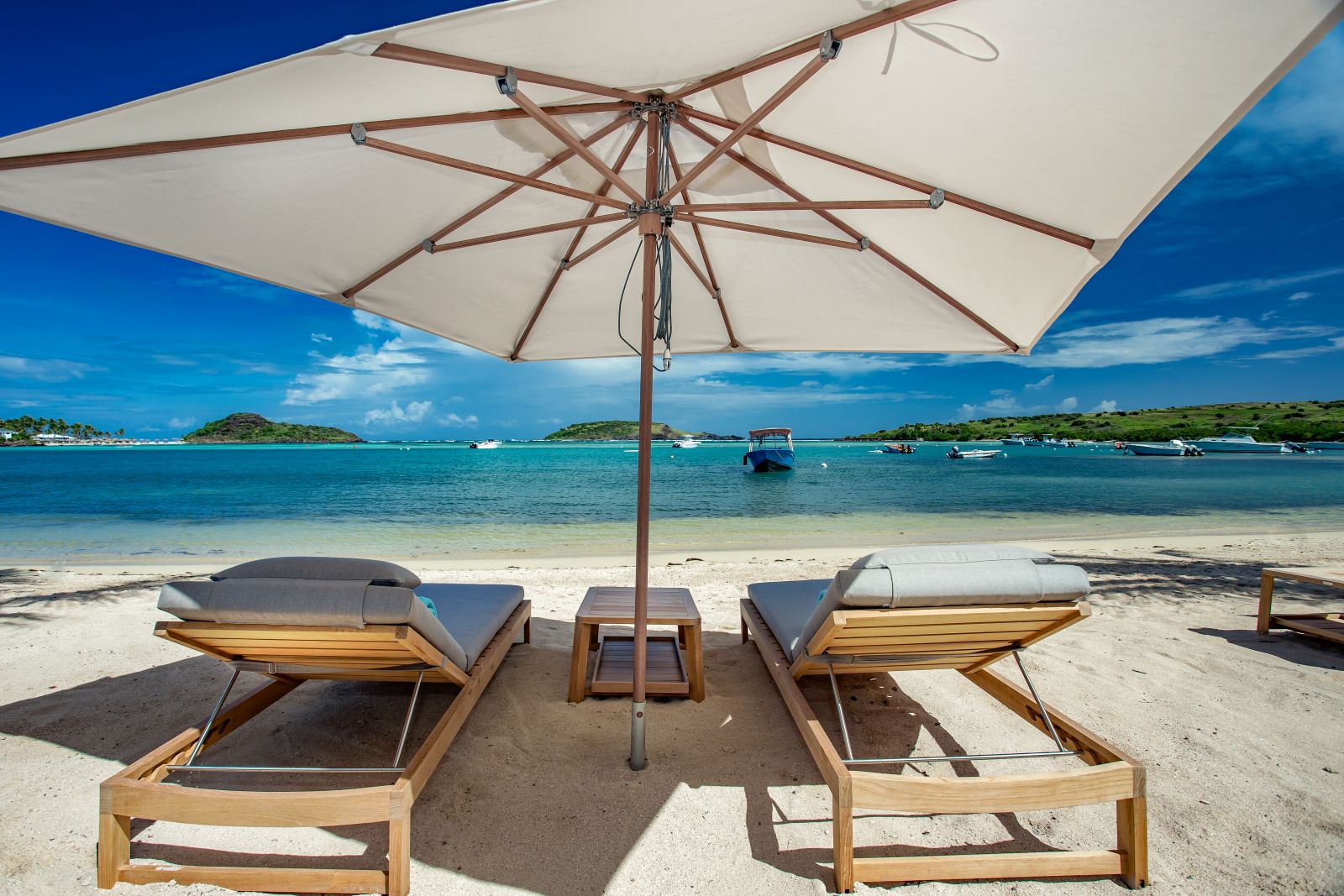 Two sun loungers under a sun umberella on the beach at Le Barthelemy Hotel & Spa in St Barths